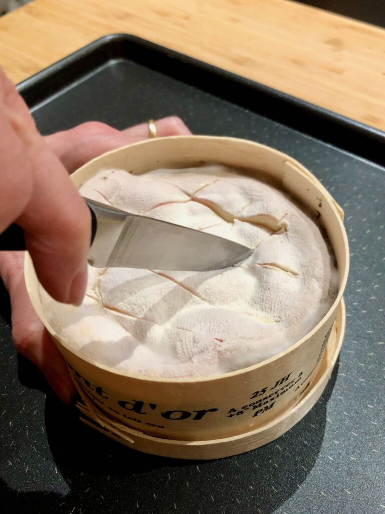 Preparing the Mont d'Or cheese by cutting diagonal lines in it