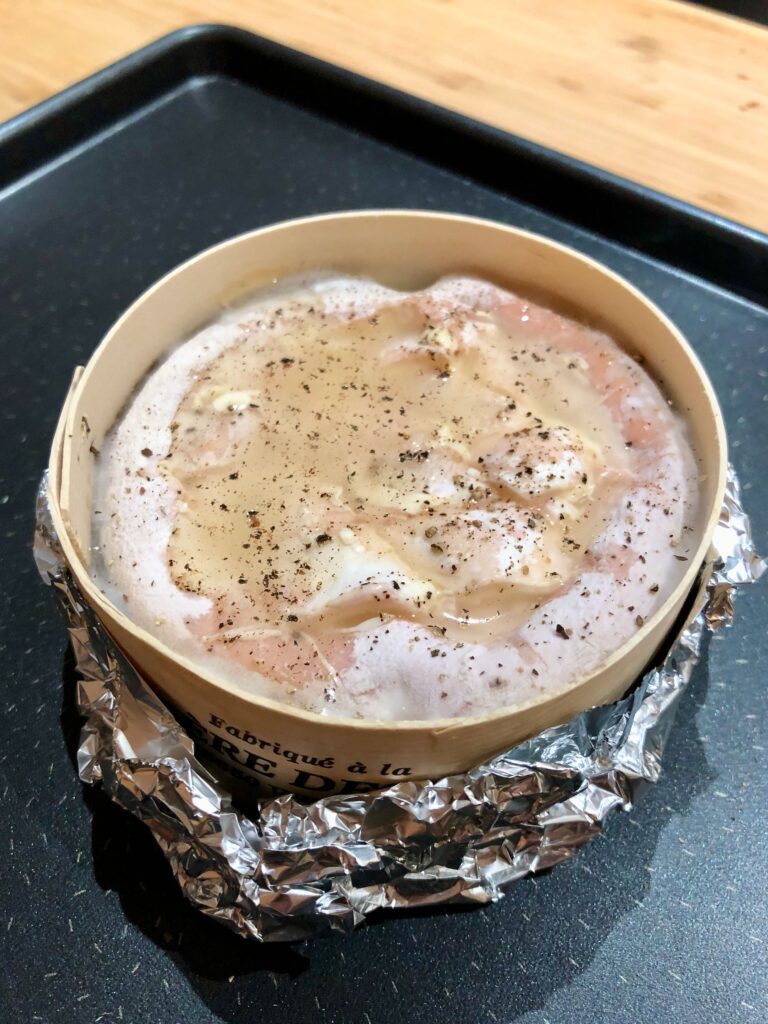 Preparing the Mont d'Or cheese with wine, garlic, and pepper