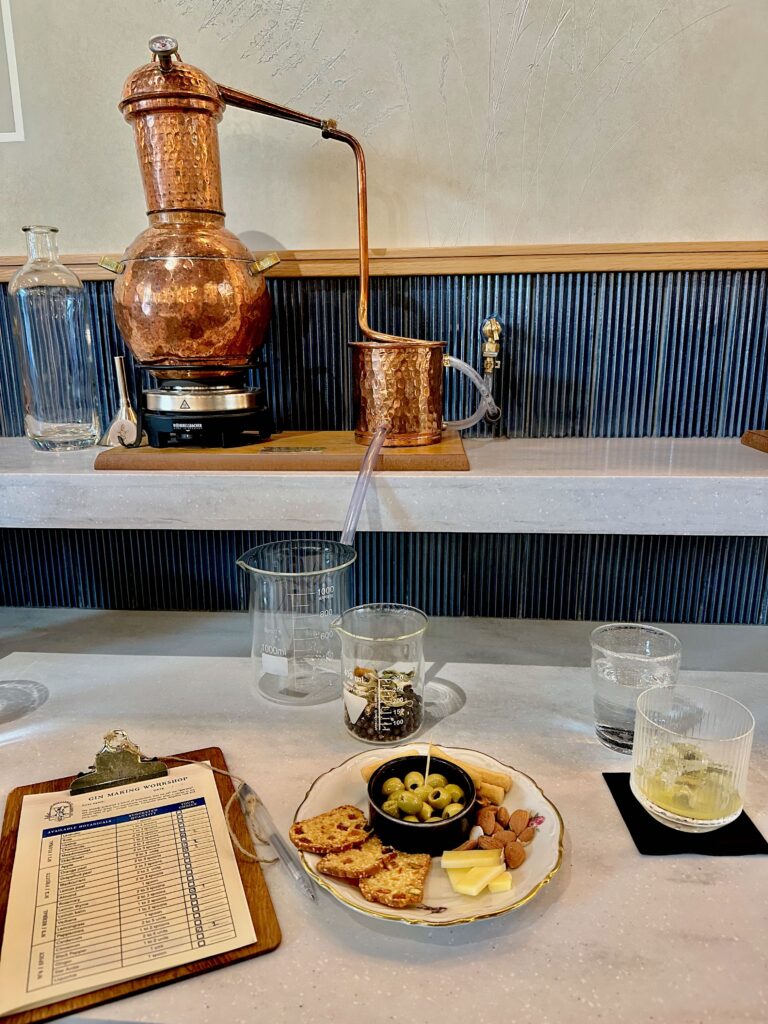 Individual workstations at Paris gin-making workshop with mini alembic still, plate of cheese and snacks, and a clipboard for notes