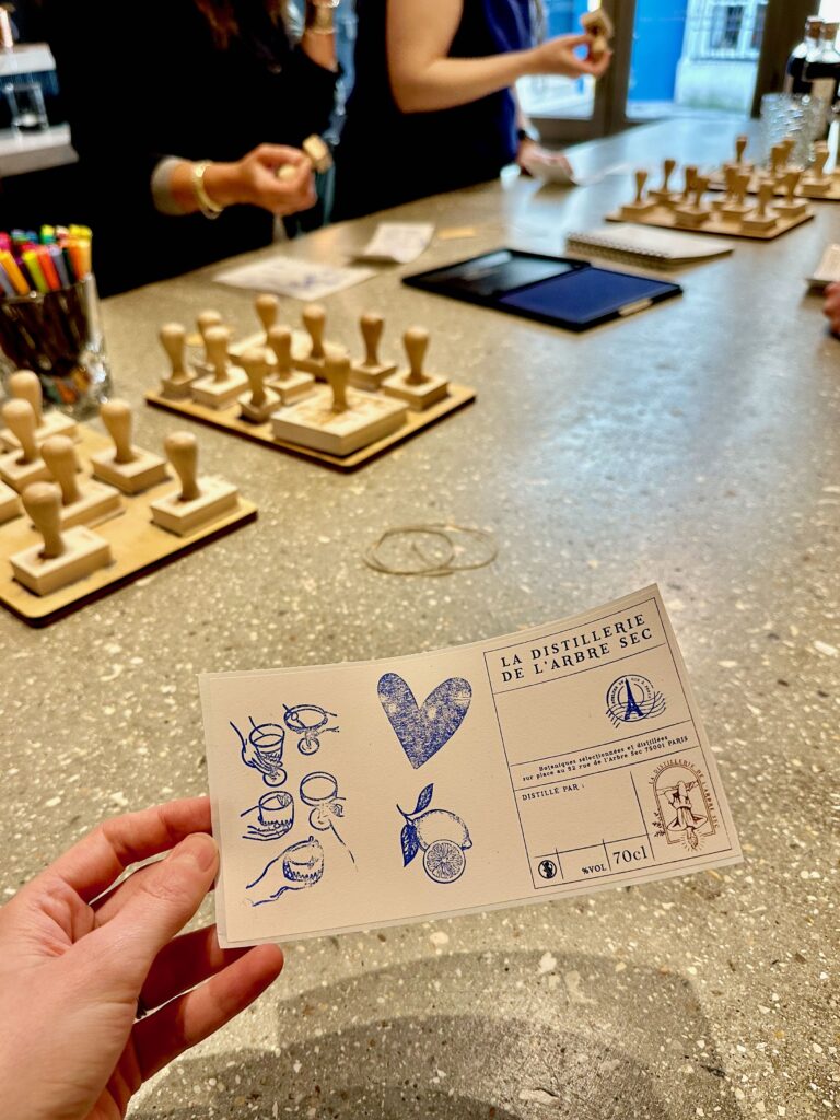 Personalizing labels with stamps and markers at a gin-making workshop in Paris