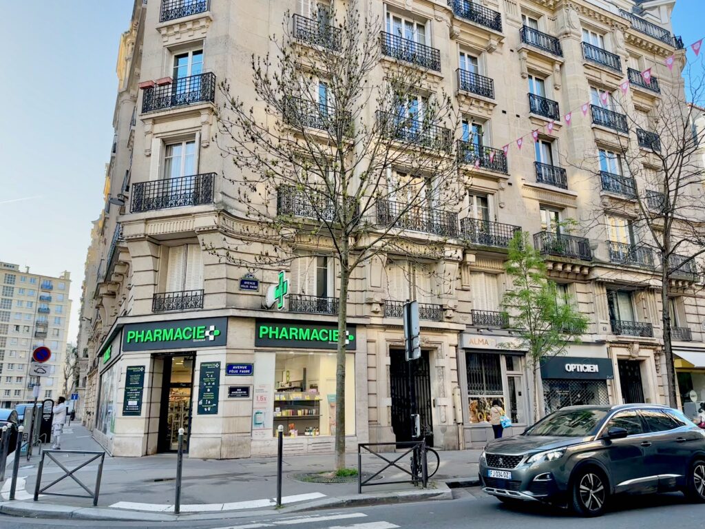 Parisian Pharmacie with illuminated green cross on a street corner