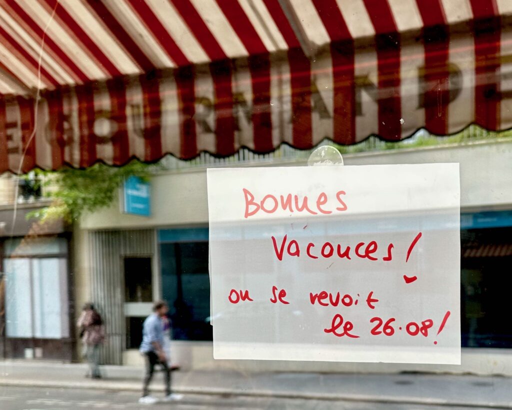 Handwritten sign indicating this Paris store is closed for the summer holidays