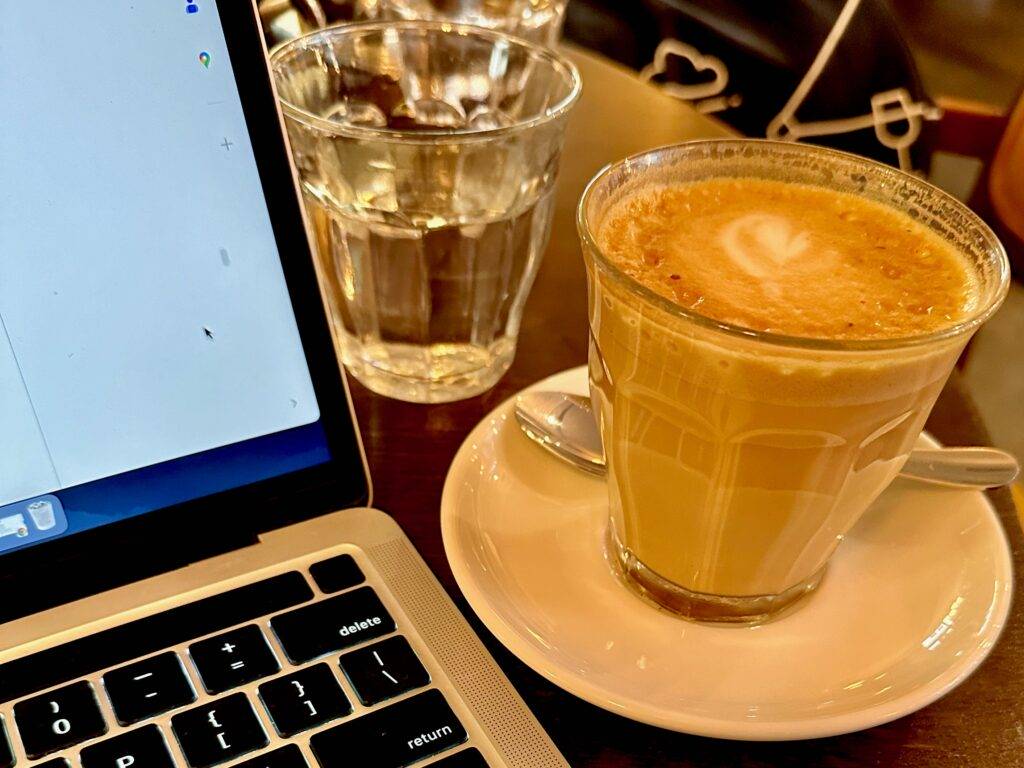 Latte next to an open laptop in a Paris coffee shop