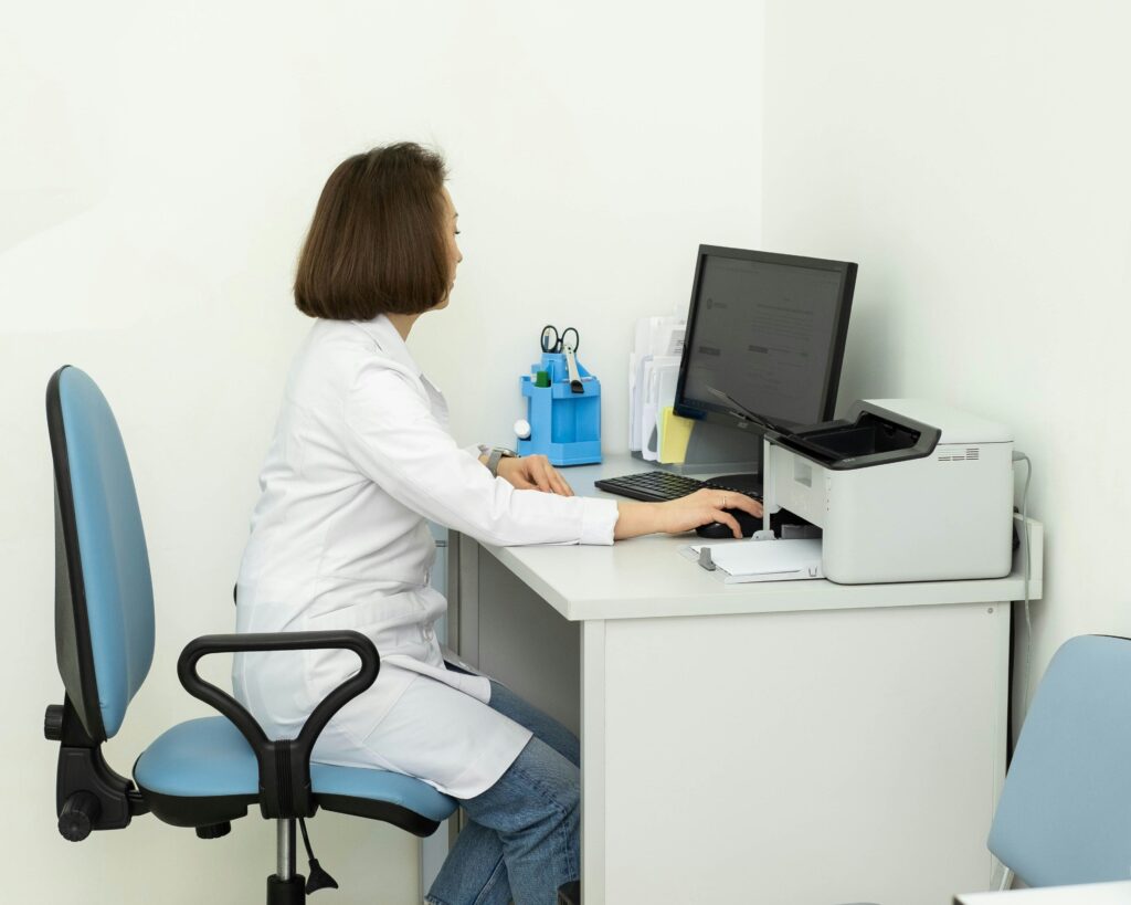 Doctor in white coat sitting at a desk on the computer