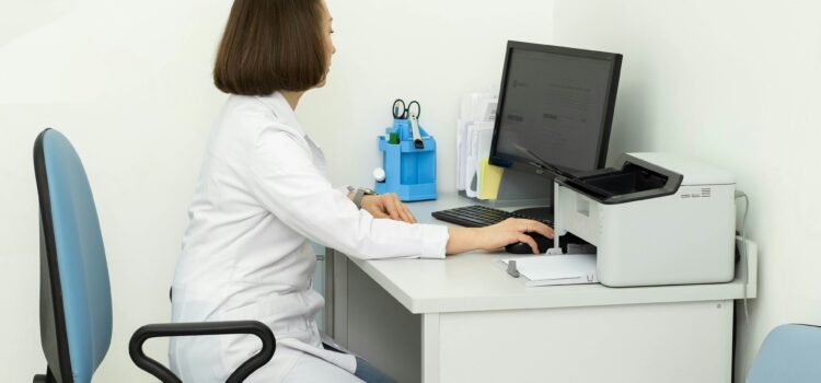 Doctor in white coat sitting at a desk on the computer
