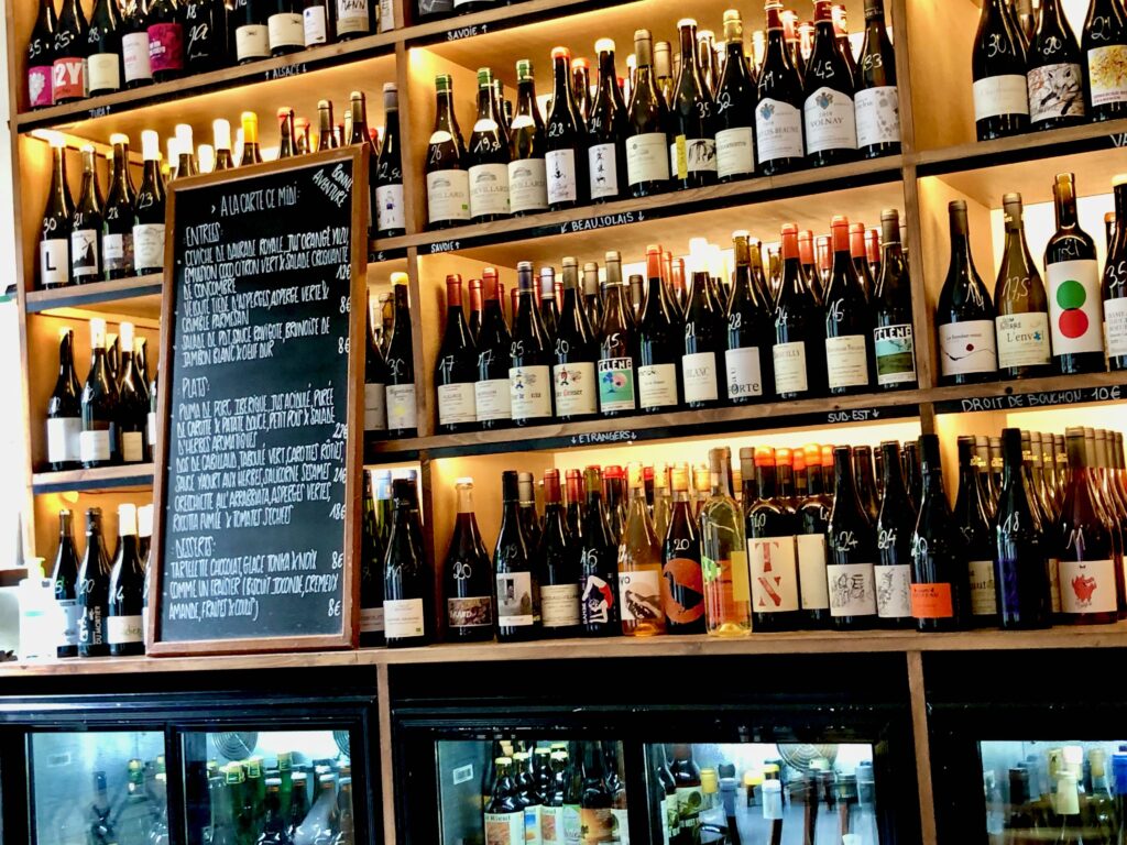 Classic French chalkboard handwritten menu on a counter in a Paris restaurant with shelves of wine bottles behind it