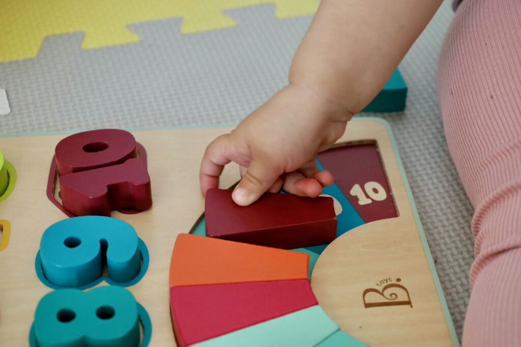 Close up of a wooden puzzle being completed by a toddler in daycare