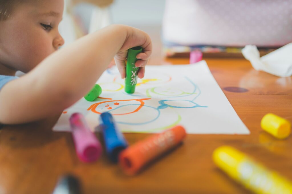 Close up of young children drawing with markers on white paper