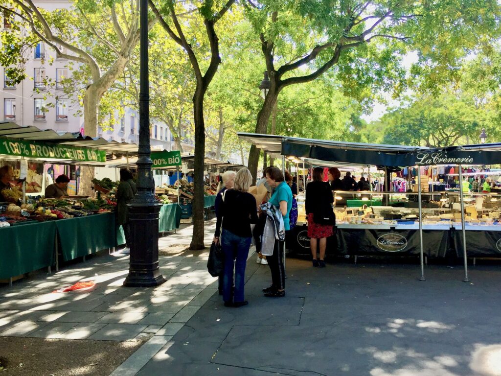 A group of women standing an chatting at a open air food market in Paris.