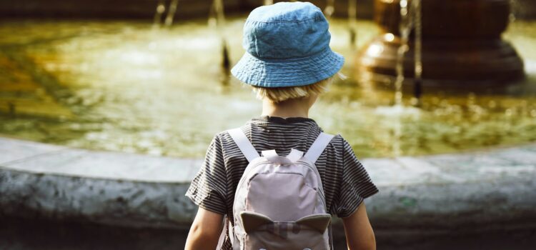 Toddler with backpack facing a fountain